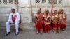 FILE: A groom (L) and four brides sit outside the venue of their weddings as they have arrived late to a mass Muslim marriage ceremony in the western city of Ahmedabad.