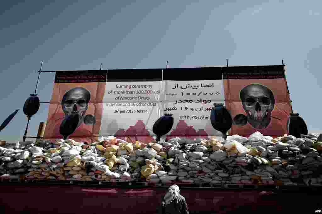 Iran -- A man stands next to a pile of drugs seized by authorities in recent months before setting it ablaze in eastern Tehran, 26Jun2013