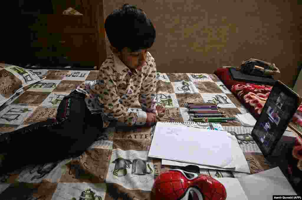 Pakistani student Mohammad Ibrahim sketches English letters at home in Islamabad as three of his classmates look on through a video-conferencing app.&nbsp; 