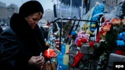 A woman lights a candle as she visits a temporary memorial for Maidan activists or 'Heroes of the Heavenly Hundred', who were killed on Kyiv's Independence Square during antigovernment protests last year. 