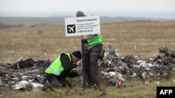 Слідчі з Нідерландів встановлюють знак поблизу місця катастрофи літака в районі села Грабове на Донеччині, листопад 2014 року