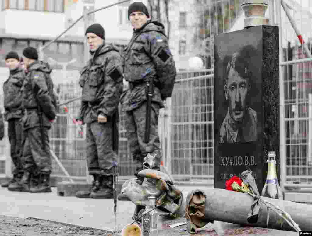 A mock gravestone depicts Russian President Vladimir Putin as former German dictator Adolf Hitler as part of a "Funeral of Putin" performance in a front of the Russian Embassy in Kyiv. Putin appeared in public on March 16 for the first time in 10 days. His unexplained absence had sparked a plethora of rumors. (Reuters/Valentyn Ogirenko)