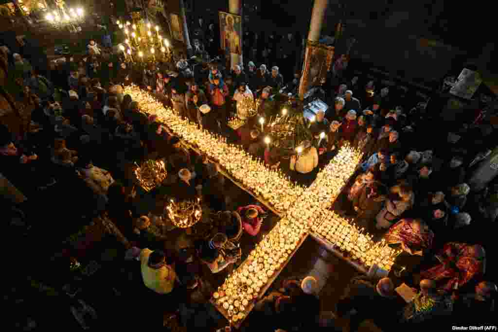 Believers attend a ceremony marking the day of St. Haralampi, protector of beekeepers, around a cross-shaped platform covered with candles placed in jars of honey, at the Church of the Blessed Virgin in Blagoevgrad, Bulgaria, on February 10.&nbsp;(AFP/Dimitar Dilkoff)