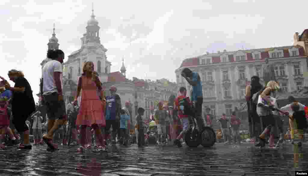 Tourists are sprayed with water to cool off on a hot day in Prague's Old Town Square. (Reuters/Petr Josek)