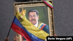 Мадуронун тарапташтары көтөрүп чыккан портрет. Каракас. 1-май, 2019-жыл.