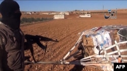 A video grab purportedly shows an IS militant pointing towards a crate attached to a parachute near the town of Kobani.