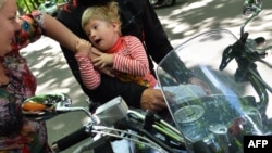 Мальчик-аутист сидит на мотоцикле.
