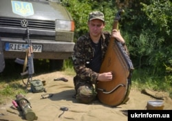 Український воїн грає на бандурі в районі Бахмутки. Луганська область, 10 липня 2015 року