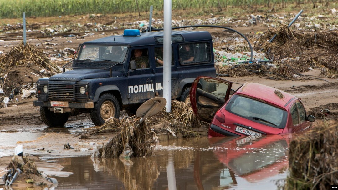 A police vehicle drives past a destroyed car near the village of Stajkovci, outside Skopje, on August 8.