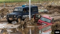 A police vehicle drives past a destroyed car near the village of Stajkovci, outside Skopje, on August 8.