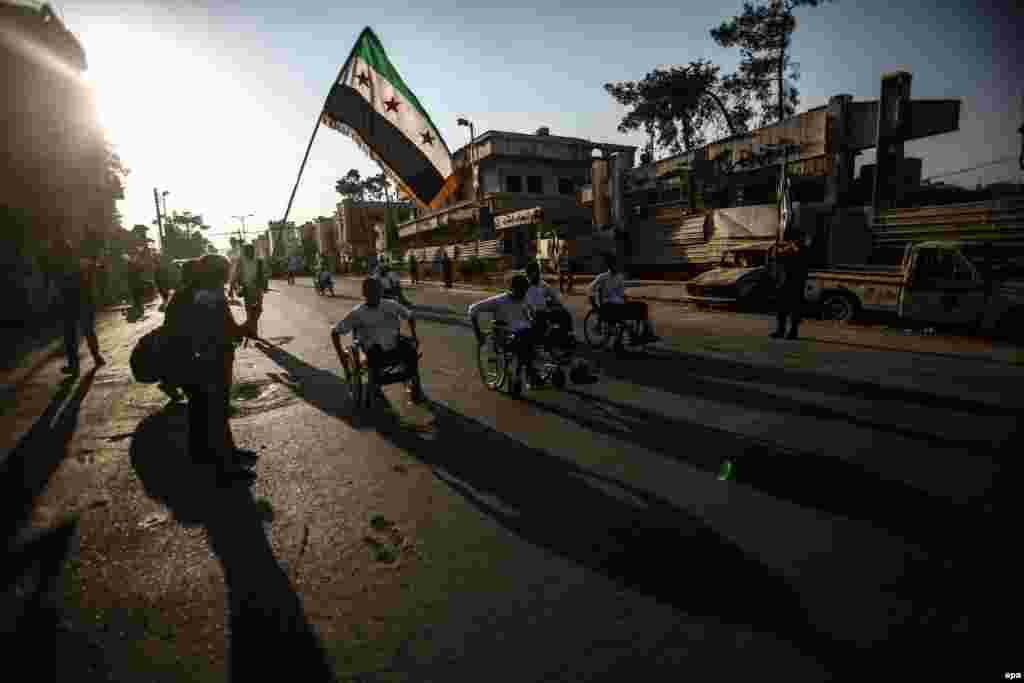 A child waves the flag of Syrian rebels as Syrians in wheelchairs participate in a race in Douma. People who suffered disabilities in the Syrian war joined the race, which was held under the slogan "Searching For Life." (epa/Mohammed Badra)