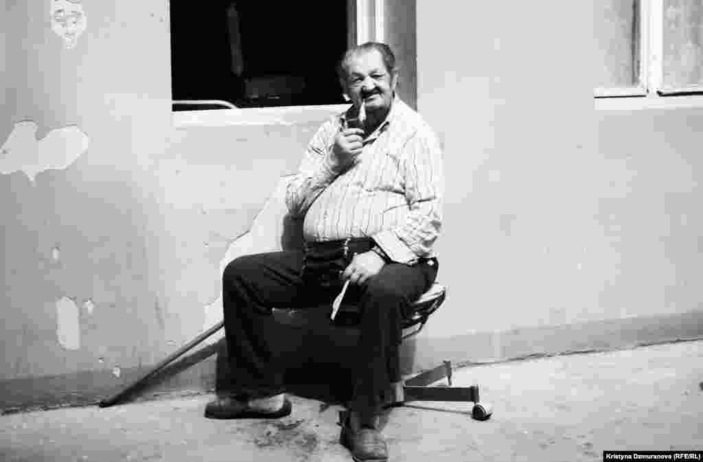 Jan Batiy enjoys his favorite pipe, which he says is one of his few remaining pleasures since his walking is now limited. He reminisces about the old days from his post in the courtyard.