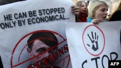 An activist in Kyiv holds a poster of Russian President Vladimir Putin caricatured as Adolf Hitler.