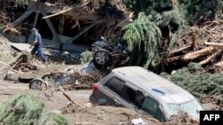 Georgia -- Men walk among damaged cars and other debris at a flooded area in Tbilisi, June 14, 2015