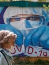 RUSSIA -- A woman wearing protective mask walks in front of a coronavirus graffiti showing a doctor with a face mask strangling with the coronavirus disease (COVID-19) pandemic on a wall in front of hospital in Krasnogorsk, Moscow region, May 15, 2020
