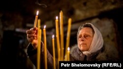 Прихожанка зажигает свечи. Иллюстративное фото.