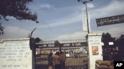 This is the entrance to the U.S. Embassy in Tehran, Iran where 63 people are being held hostage, seen in 1980. Graffiti on the wall at left reads: "Dear American minority, brothers and sisters (Blacks and Indians) study the holy Koran and start a revolu