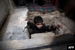 A Syrian boy climbs out of a bomb shelter in the rebel-held town of Douma, on the eastern outskirts of Damascus, on October 30.