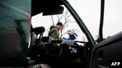 Наблюдатель ОБСЕ и пророссийский сепаратист осматривают автомобиль, попавший под обстрел у села Широкино