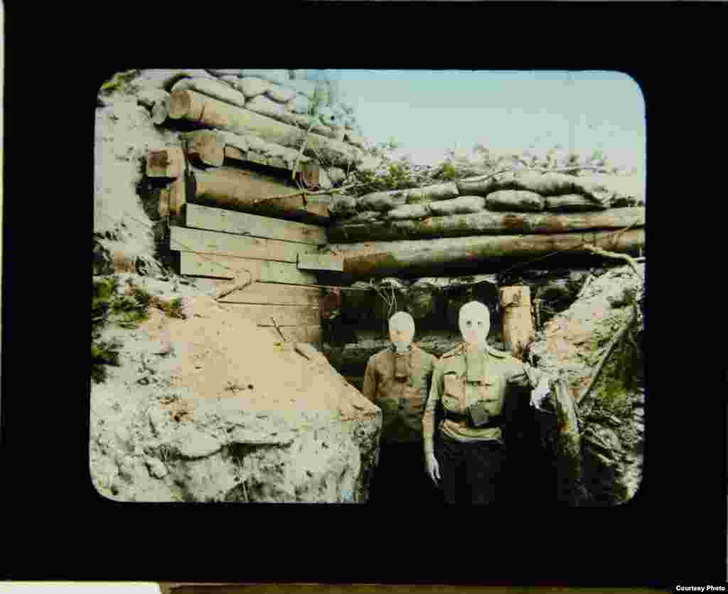 Soldiers wearing gas masks pose by a bunker.