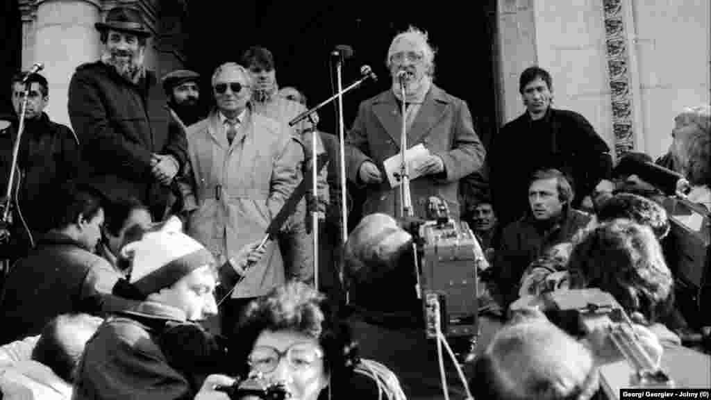 Част от ораторите на първия митинг на опозицията от 18.11.1989 г. Отляво на дясно: икономистът Петър Гогов (зад микрофона), зоологът Петър Берон (с шапката), работникът Любомир Собаджиев (с каскет и брада), сценаристът Анжел Вагенщайн (с тъмните очила), неидентифициран участник, сатирикът Радой Ралин (говори пред микрофона). Спомените на очевидци са единодушни: инициаторът на този митинг е Анжел Вагенщайн (р.1922 г.), който по-късно преминава към БСП и никога не се отказва от левите си убеждения.