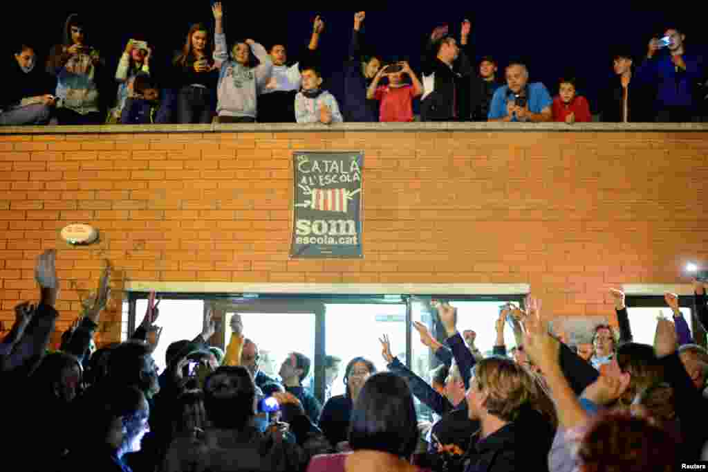 Люди празднуют завершение каталонского референдума у избирательного участка в городе Бик