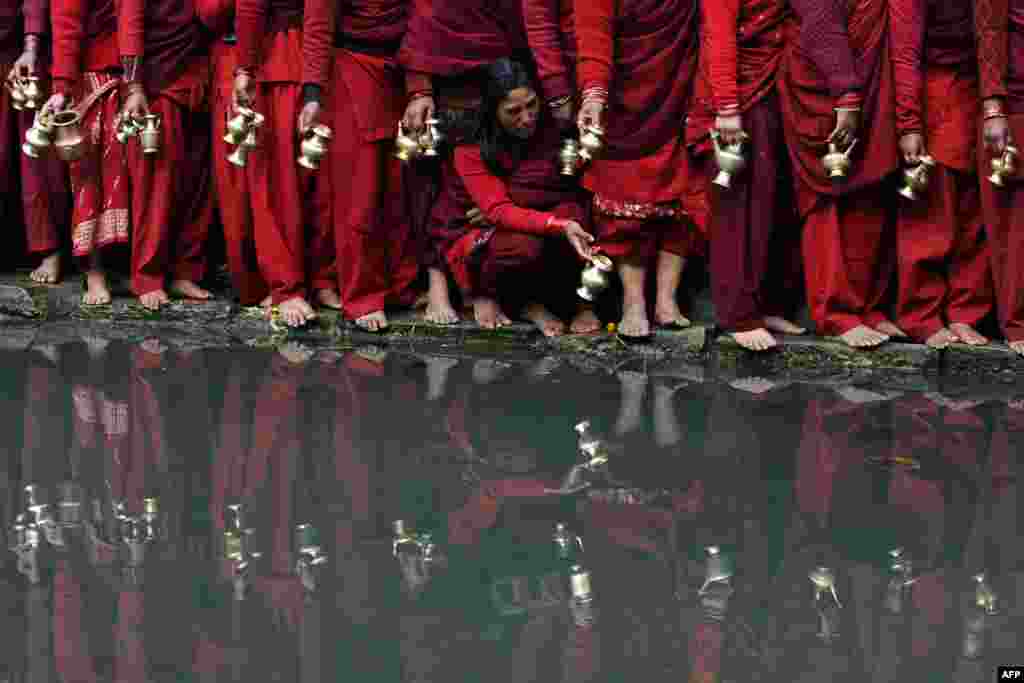 Hindu devotees wait to fill pots with water from the Bagmati River at the Pashupatinath Temple during the monthlong Swasthani festival in Kathmandu. (AFP/Prakash Mathema)