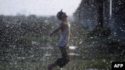 Pakistani youth cool off under a leaking water pipeline during a heat wave in Karachi in May.