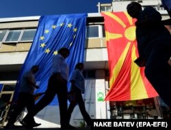 Cetățenii trec pe lângă steagurile UE și ale Macedoniei de Nord (dreapta), în timpul marșului pentru Macedonia Europeană în centrul capitalei Skopje, 16 septembrie 2018. EPA-EFE/NAKE BATEV