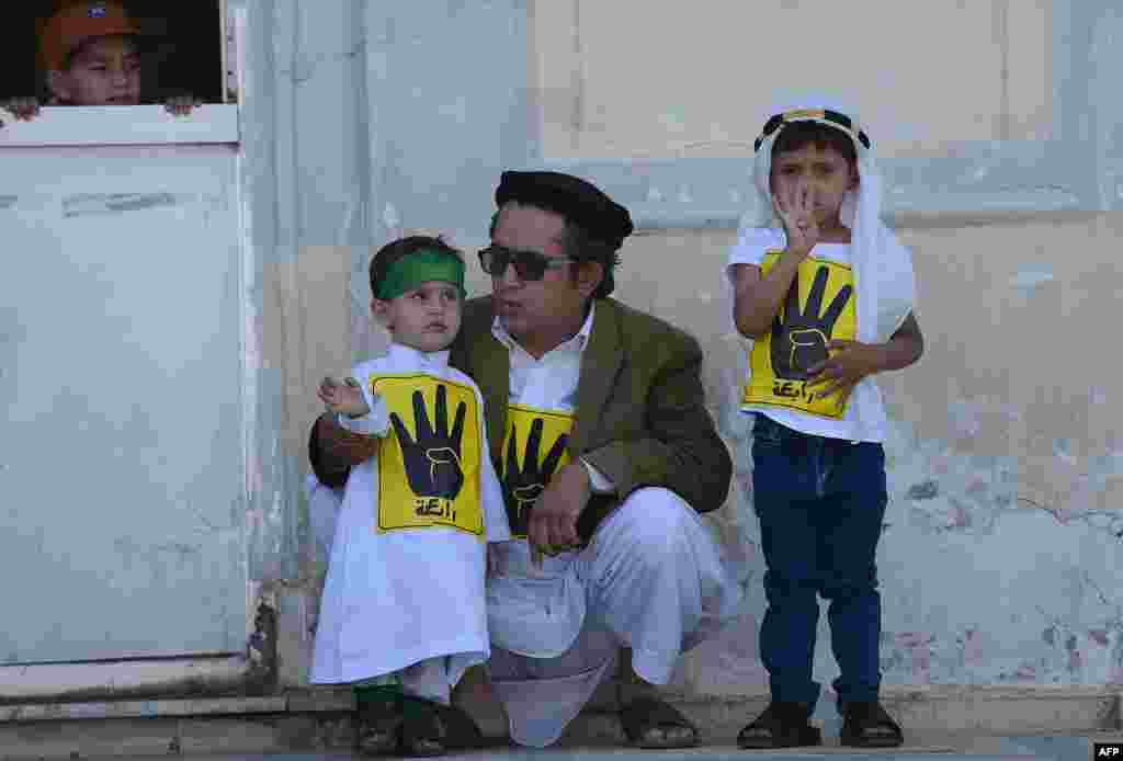 Двое детей вместе с отцом наблюдают за участниками кабульской демонстрации в поддержку отстраненного от власти в результате военного переворота президента Египта Мухаммеда Мурси.
