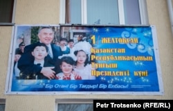 Праздничный плакат на фасаде школы, в которой учился Нурсултан Назарбаев. Шамалган, 28 ноября 2018 года.