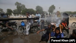 A volunteer sprays water on people to keep them cool as temperatures reached 44 Celsius in Karachi on May 21.