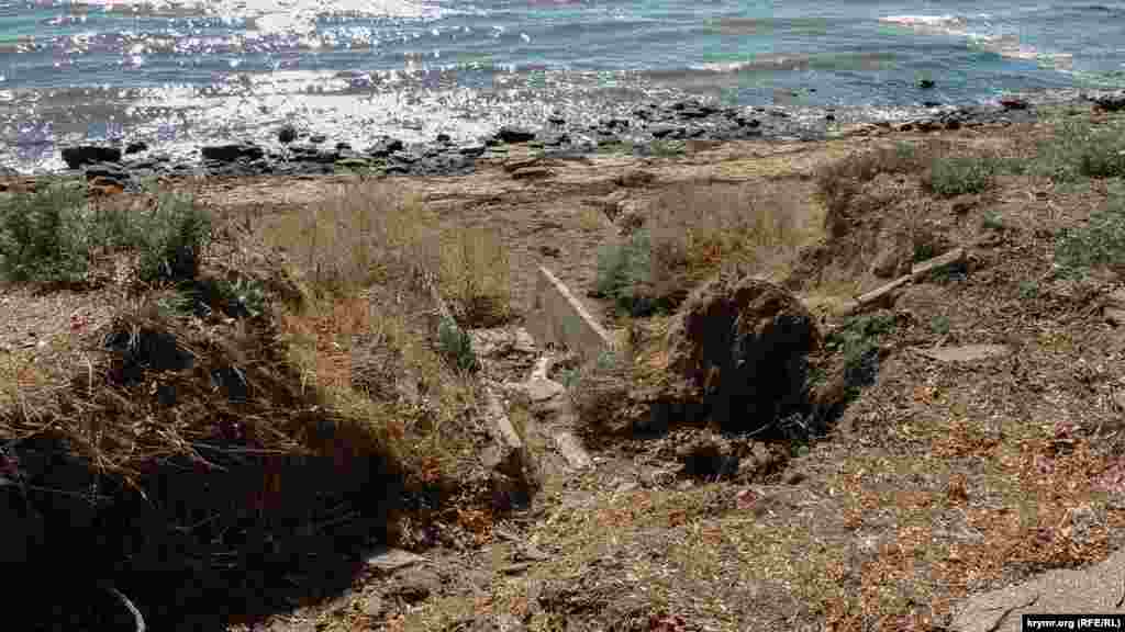 Размытая ливневка, разрушенный берег и асфальтированная дорожка вдоль пляжа. Асфальтовое покрытие разрушается из-за размытия грунта