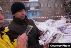 Туыстары қаза тапқан Алексей Алексеенко мерт болған адамдардың суреттерін көрсетіп тұр. Шахан, 2 қаңтар 2017 жыл.