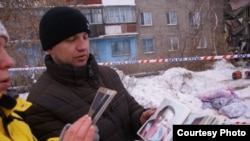 Алексей Алексеенко, родственник погибших в результате обрушения дома, показывает фото погибшей с полугодовалым ребенком. Шахан, 2 января 2017 года.