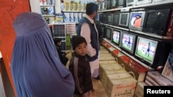Afghanistan -- A family stands at a TV and satellite shop in Herat, 12Dec2009