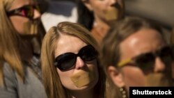 Journalists protest with taped mouths against censorship.