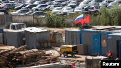 Russia -- Workers gather at a construction site near cars, produced by foreign automobile-makers, which are seen at a parking of a dealership in the background, on the outskirts of Moscow, August 18, 2014