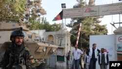 MSF staff and Afghan military personnel stand outside the entrance to the bombed hospital in Kunduz on October 15, 2015.