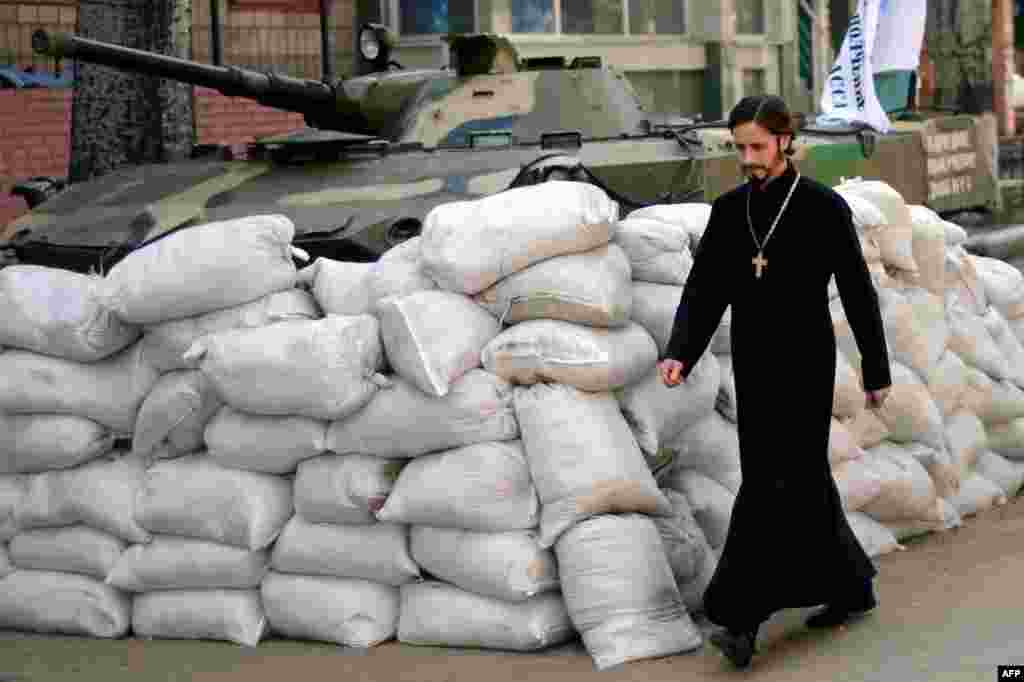 Священик проходить повз барикад біля захопленої проросійськими бойовиками будівлі СБУ у Слов&#39;янську, 23 квітня 2014 року