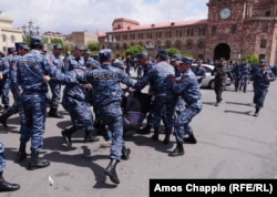 A policeman kicks a demonstator as he is dragged into a police van in Yerevan's Republic Square on April 22.