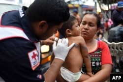 Врач мексиканской скорой помощи помогает одной из беженок с ребенком. 24 октября 2018 года