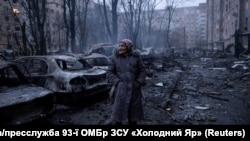 Жінка біля багатоповерхівок та машин, які були пошкоджені внаслідок російського авіаудару, Краматорськ, Донецька область, 8 лютого 2026 року