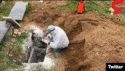 A grave is dusted with quicklime for disinfection against the coronavirus in Mazandaran, Iran, on April 7.