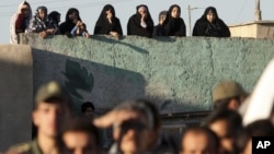 Iranians watch the public execution of a convicted man in the city of Qazvin in May 2011.