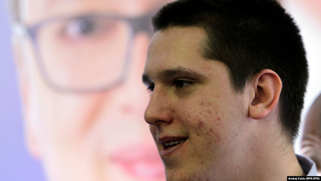 Danilo Vučić stoji ispred plakata na kome je njegov otac Aleksandar, fotoarhiv