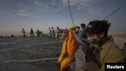 FILE: A Hindu devotee, with his face painted from its sacred mud, prays at the crater of the Chandargup mud volcano during a pilgrimage to the Shri Hinglaj Mata Temple in Pakistan's southwestern Balochistan Province in April 2011.