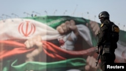 Un membru al poliției iraniene supraveghează un miting pro-regim organizat la Teheran, Iran, 12 ianuarie.