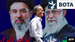 Një burrë duke kaluar pranë një pankarte të udhëheqësit suprem të Iranit, Ajatollah Mojtaba Khamenei, dhe të atit të tij të ndjerë, Ali Khamenei. Teheran, 6 maj 2026.