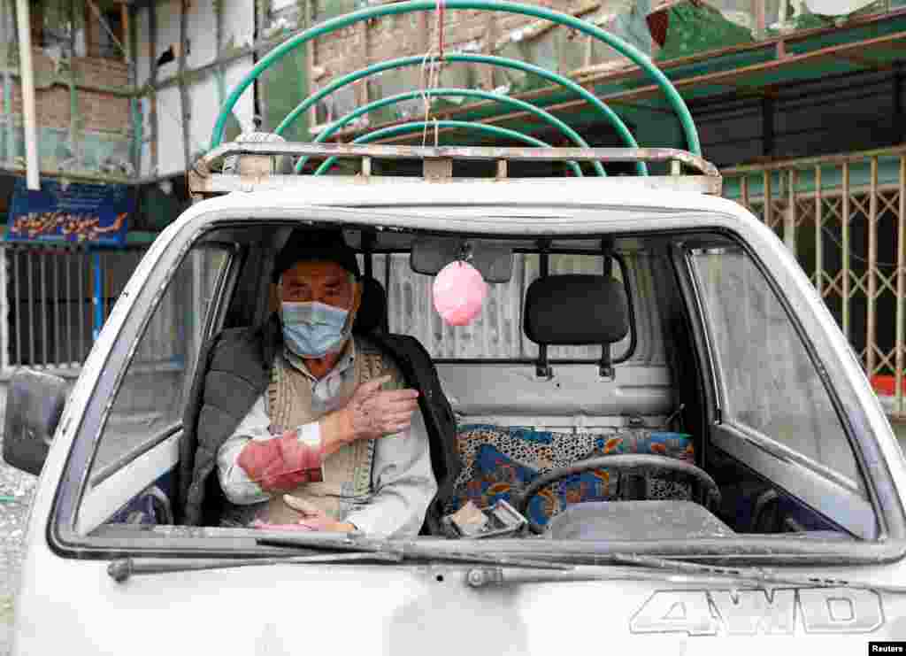 An injured man sits inside a damaged vehicle at the site of a bomb blast in Kabul, Afghanistan, on December 20. (Reuters/Mohammad Ismail)&nbsp;